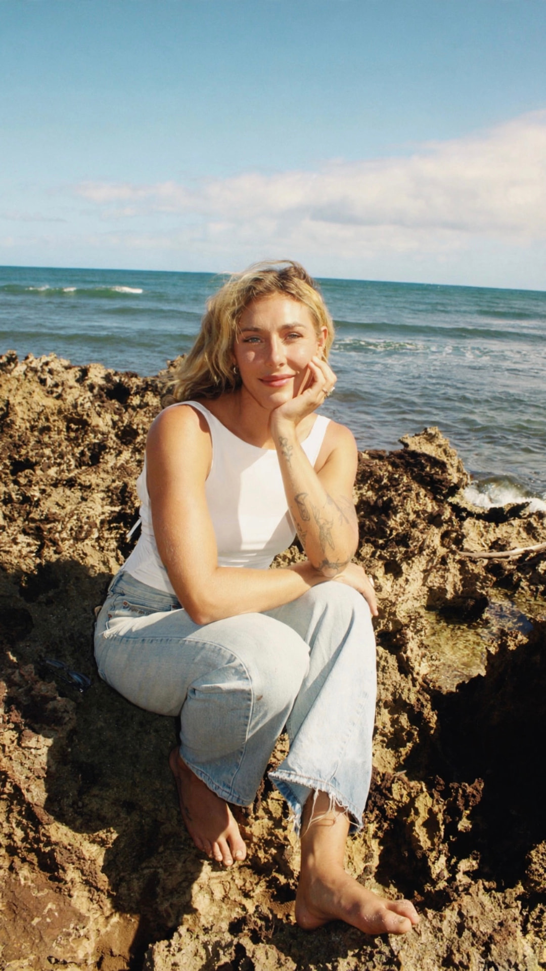 Brittany Bostick sitting on coastal rocks by the ocean